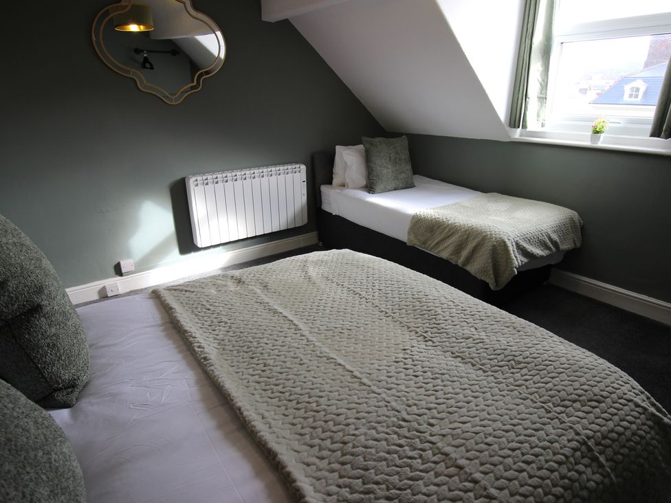 A bedroom with a double and single bed at Cornerhouse Apartment 1 in Llandudno