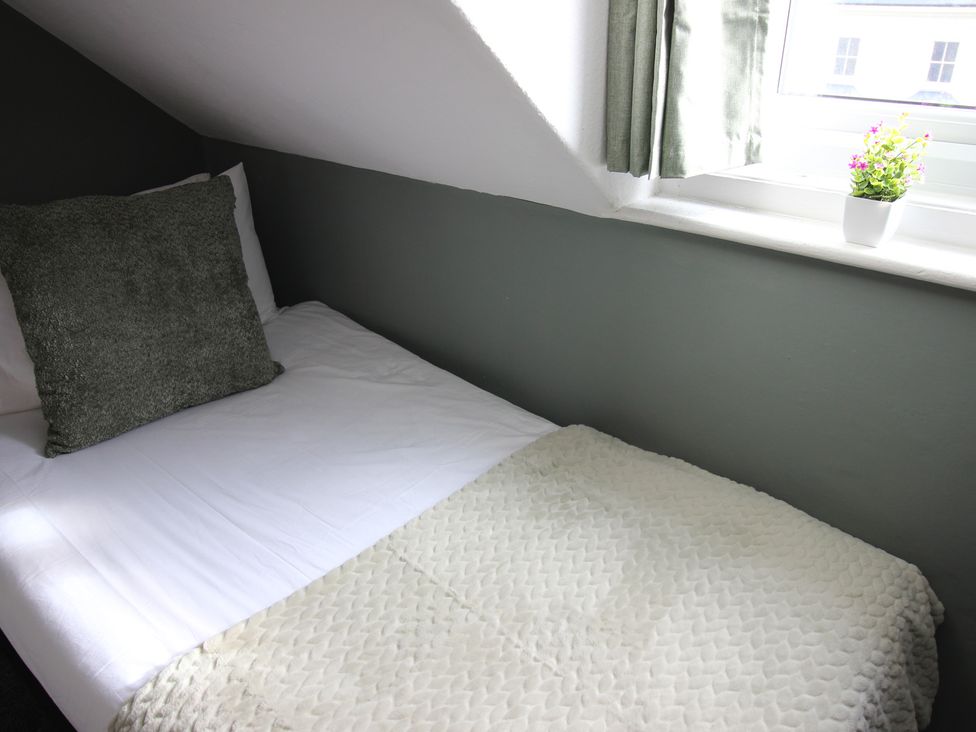 A bed with a pillow and blanket in a bedroom at Cornerhouse Apartment 1 in Llandudno