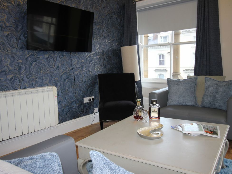 A living room with a television and seating at Cornerhouse Apartment 2 in Llandudno