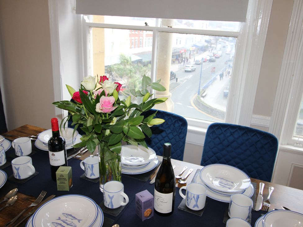 A dining room table set with plates and wine bottles at Cornerhouse Apartment 2 in Llandudno