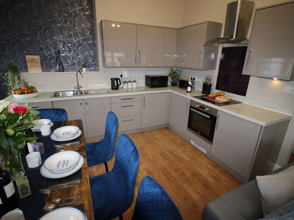 A kitchen with cabinets, sink, and appliances at Cornerhouse Apartment 2 Llandudno