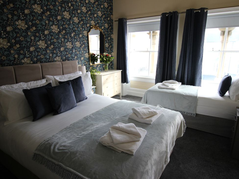 A bedroom with two beds and a dresser at Cornerhouse Apartment 2 Llandudno