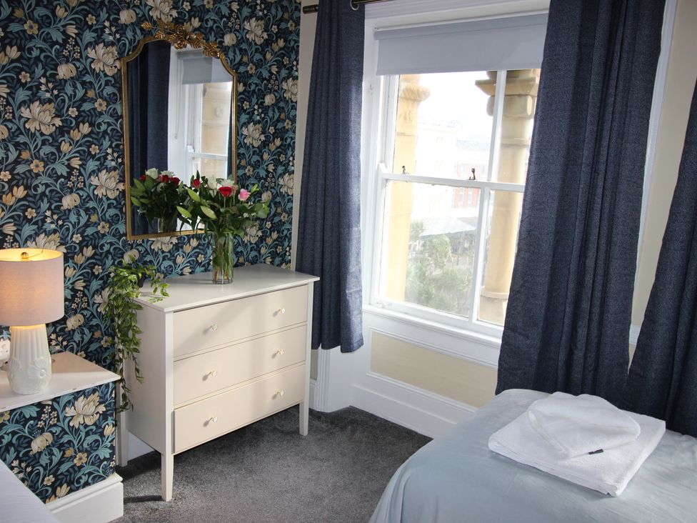 A bedroom with a mirror and chest of drawers at Cornerhouse Apartment 2 in Llandudno