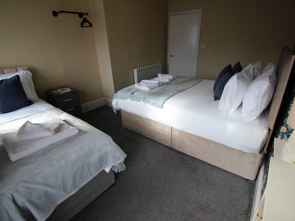 A bedroom with two beds and a bedside table at Cornerhouse Apartment 2 in Llandudno