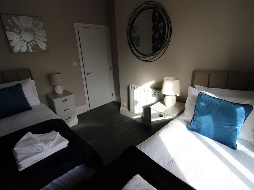 A bedroom with two beds and a mirror at Cornerhouse Apartment 2 in Llandudno