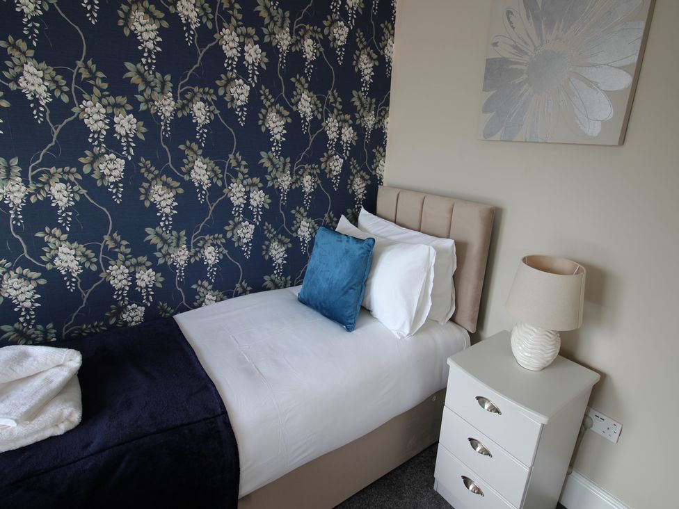 A bedroom with a bed and a bedside table at Cornerhouse Apartment 2 in Llandudno
