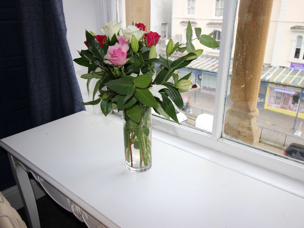 A vase with flowers on a table at Cornerhouse Apartment 2 in Llandudno