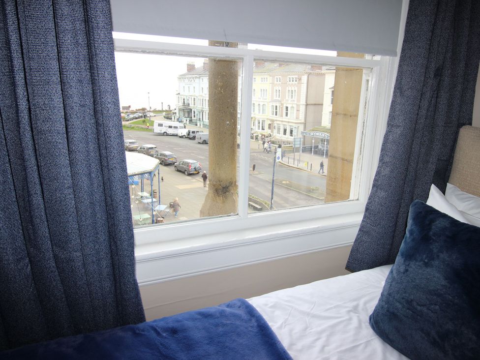 A window view showing a street with cars and buildings at Cornerhouse Apartment 2 in Llandudno