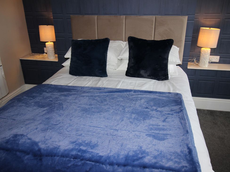 A bedroom with a bed and bedside lamps at Cornerhouse Apartment 2 in Llandudno