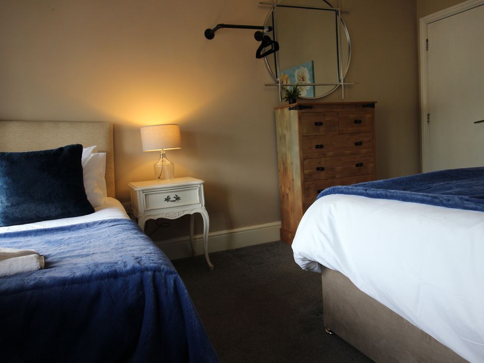 A bedroom with two beds and a dresser at Cornerhouse Apartment 2 in Llandudno
