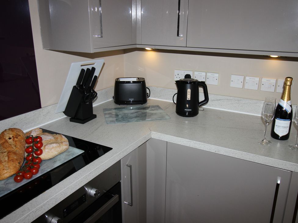 A kitchen with a kettle, toaster, and various items on the countertop at Cornerhouse Apartment 3 in Llandudno