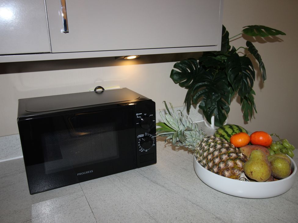 A kitchen with a microwave and a fruit bowl at Cornerhouse Apartment 3 in Llandudno