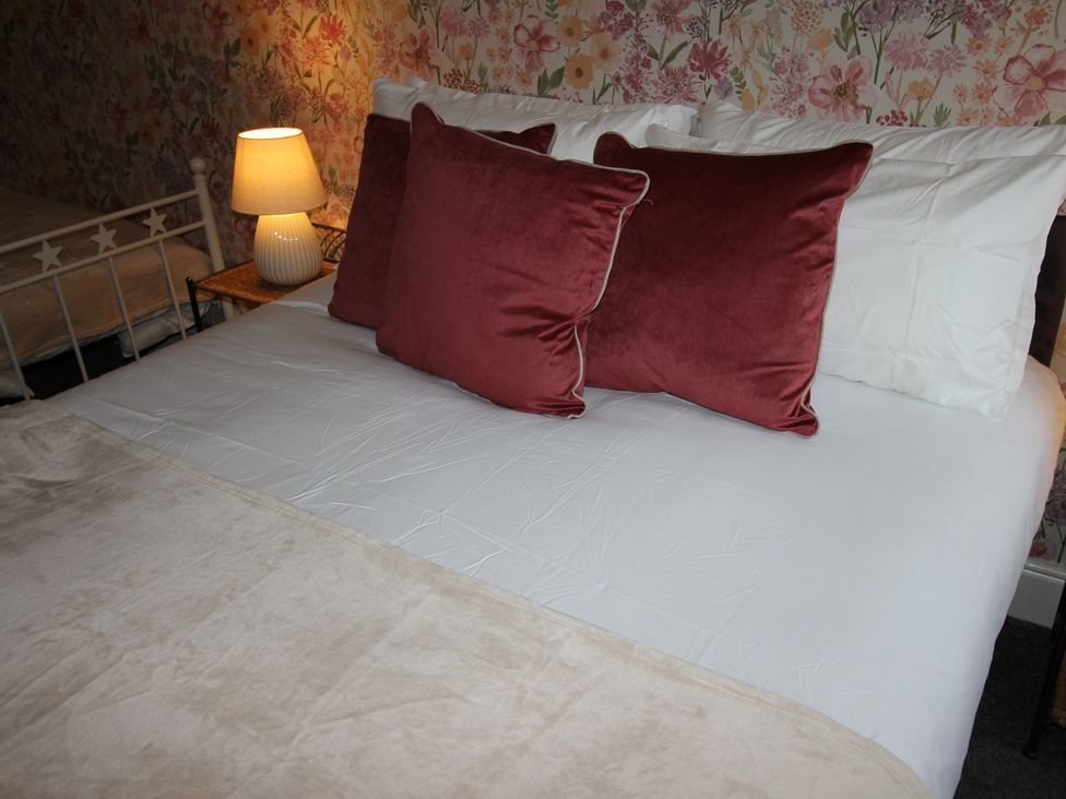 A bedroom with a bed and a bedside lamp at Cornerhouse Apartment 3 in Llandudno