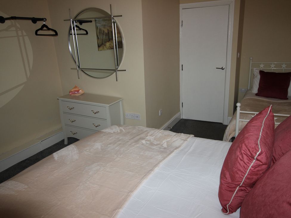A bedroom with a bed, dressing table, and mirror at Cornerhouse Apartment 3 Llandudno