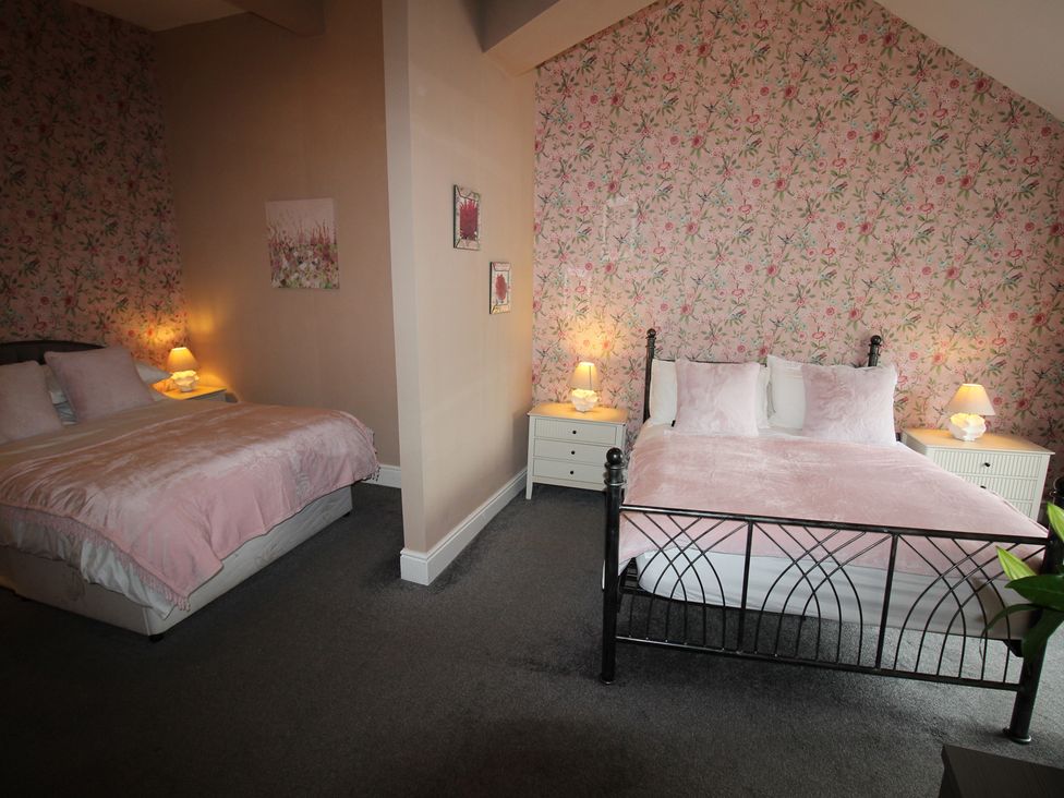 A bedroom with two beds and nightstands at Cornerhouse Apartment 3 Llandudno