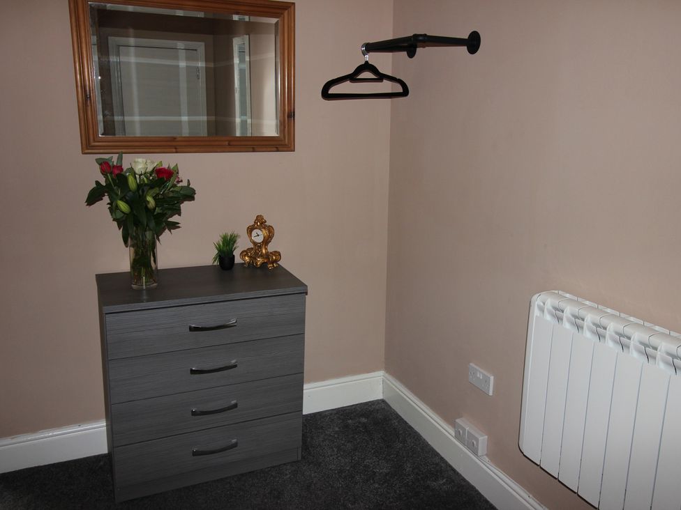A bedroom with a drawer unit and mirror at Cornerhouse Apartment 3 Llandudno