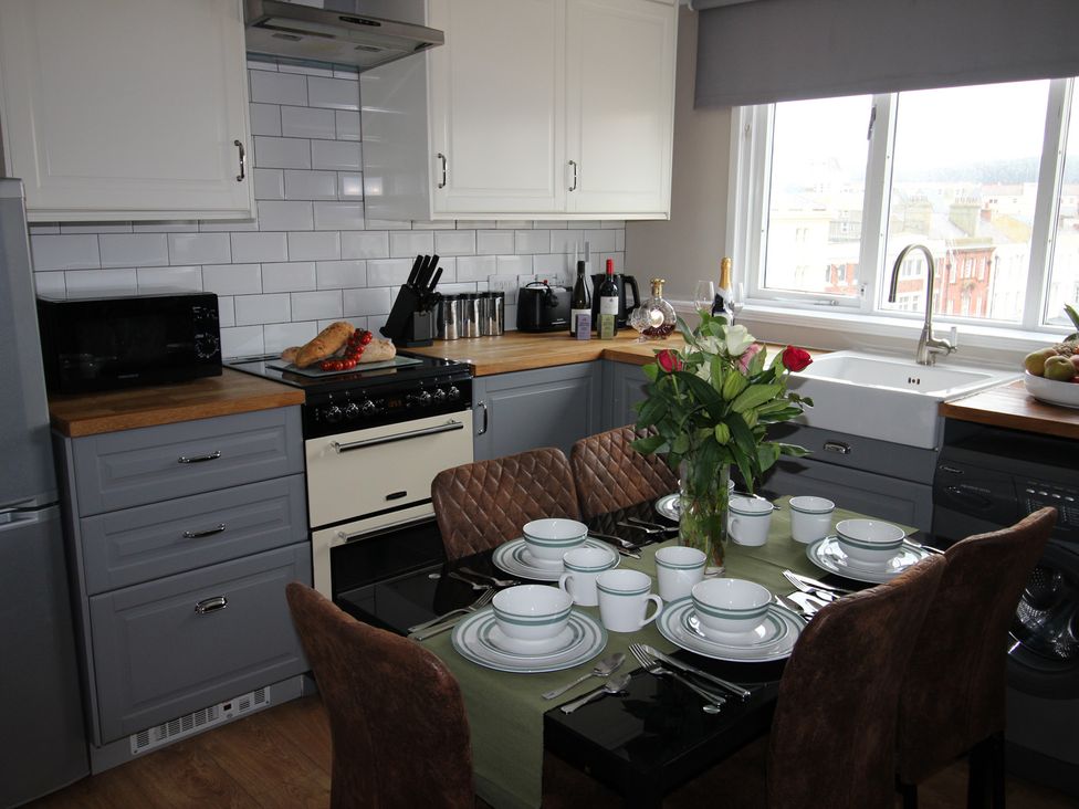 A kitchen with dining table and chairs at Cornerhouse Apartment 4 in Llandudno