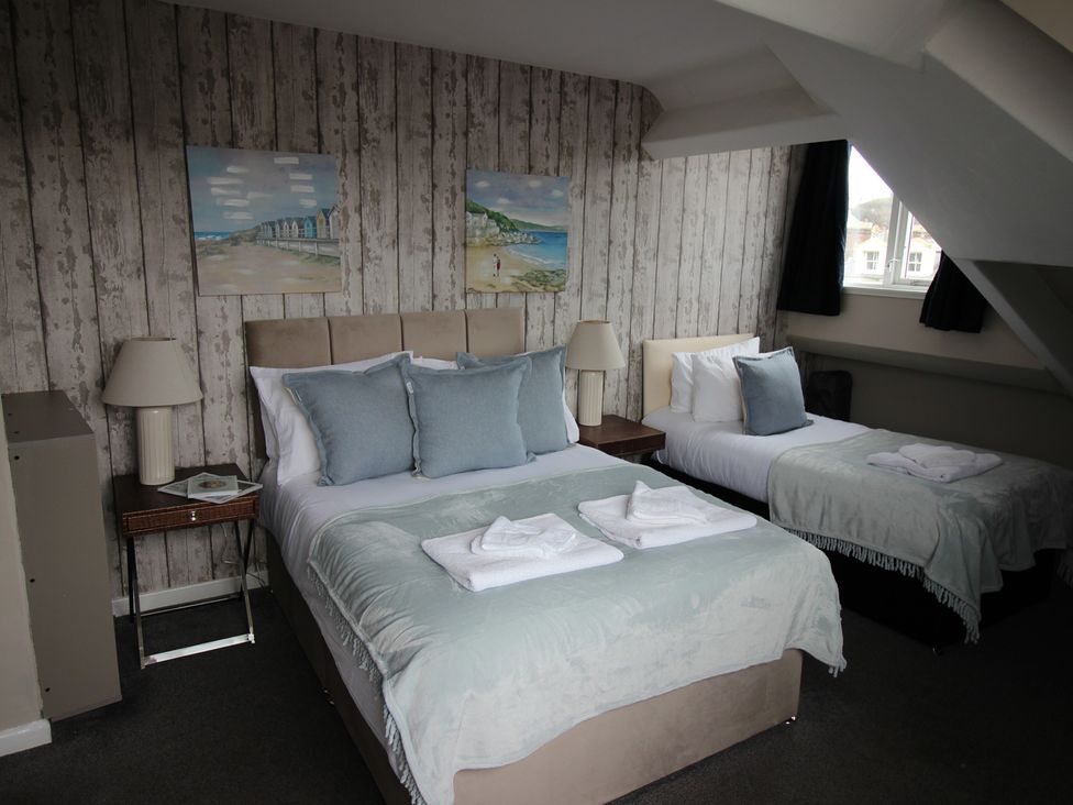 A bedroom with two beds and paintings on the wall at Cornerhouse Apartment 4 in Llandudno