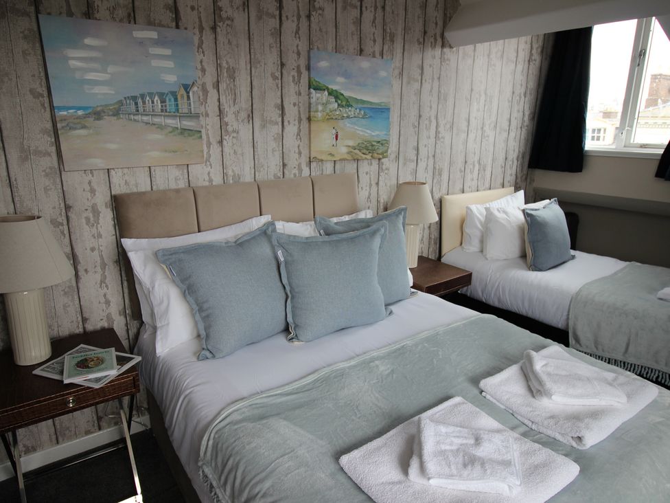 A bedroom with two beds and artwork on the wall at Cornerhouse Apartment 4, Llandudno