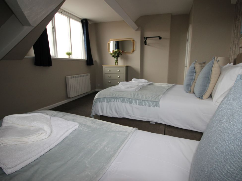 A bedroom with two beds and a mirror at Cornerhouse Apartment 4, Llandudno