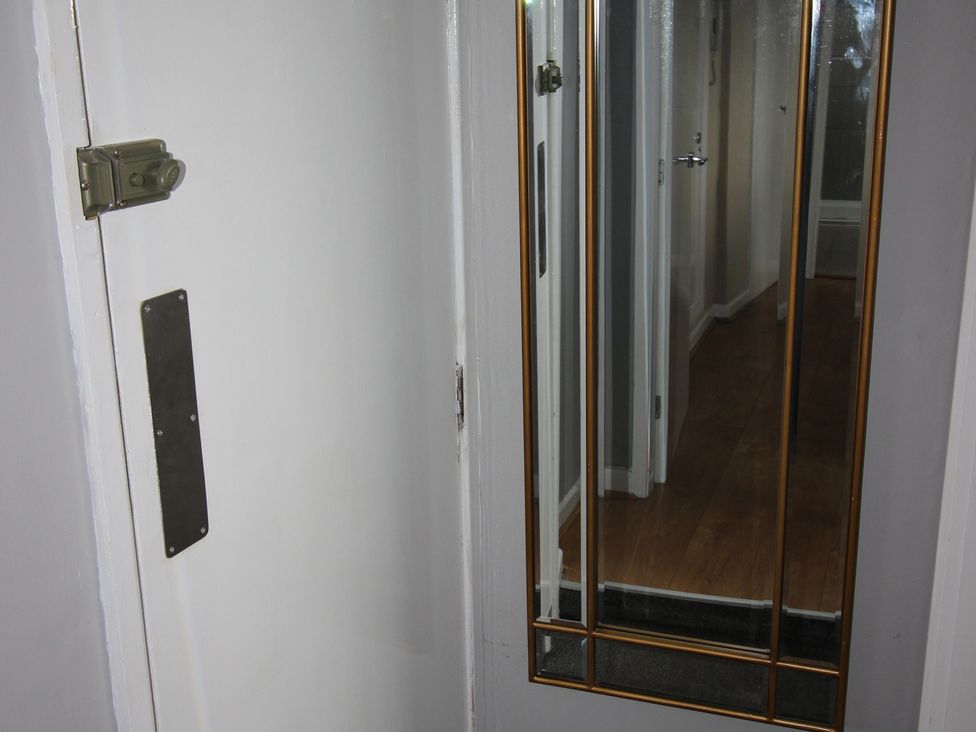 A hallway with a door and a mirror at Cornerhouse Apartment 4 in Llandudno