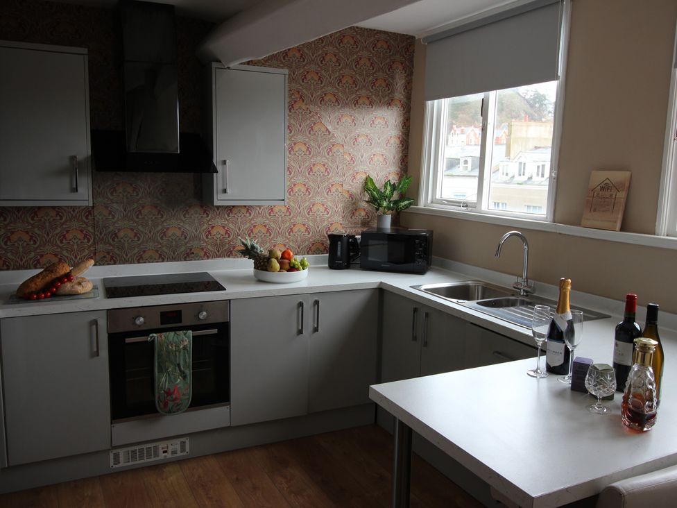 A kitchen with oven, sink, and table at Cornerhouse Apartment 5 in Llandudno