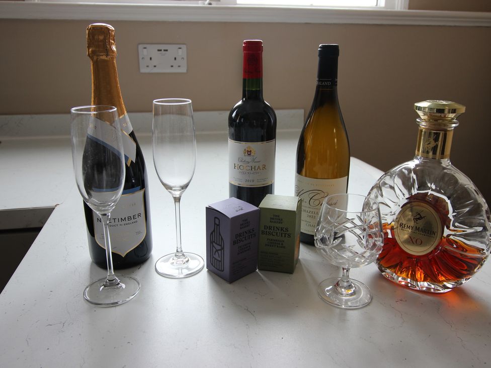 A kitchen counter with wine bottles and glasses at Cornerhouse Apartment 5 Llandudno