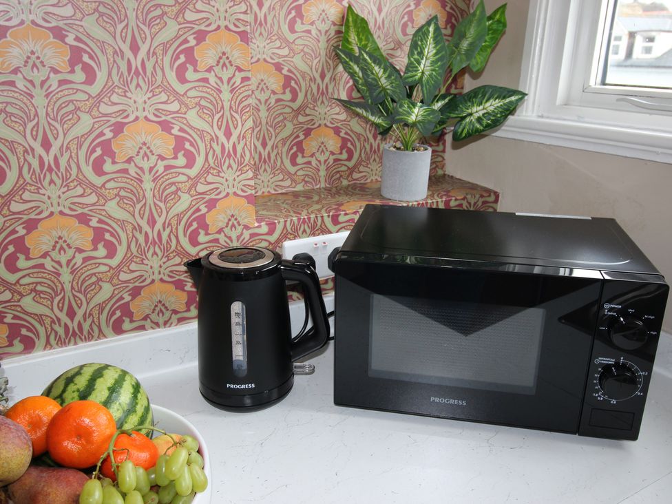 A kitchen with a microwave, kettle, and fruit bowl at Cornerhouse Apartment 5, Llandudno