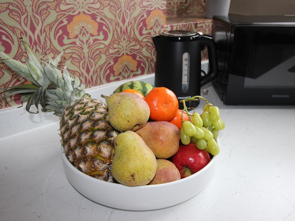 A fruit bowl with various fruits and a kettle in the kitchen at Cornerhouse Apartment 5 Llandudno