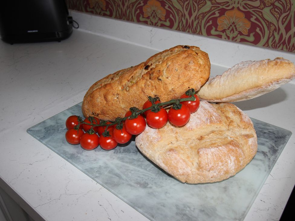 Breads and tomatoes on a cutting board at Cornerhouse Apartment 5 in Llandudno