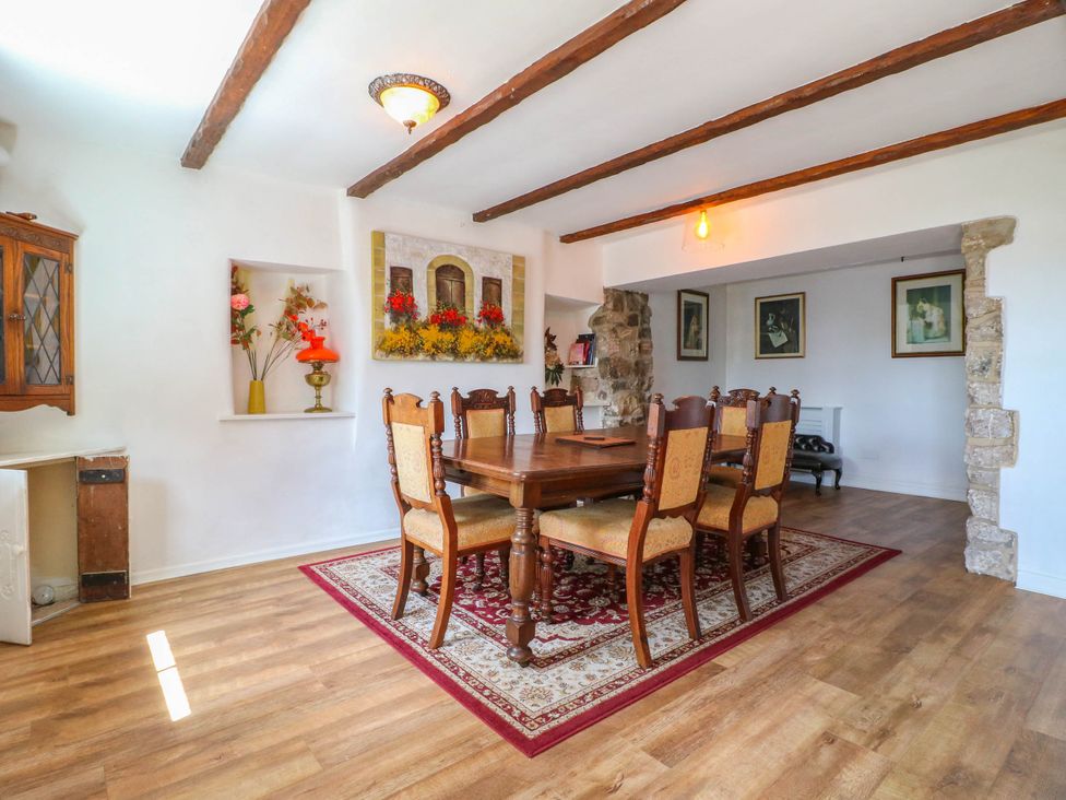 A dining room with a wooden table and eight chairs at Jasmine Cottage in Matlock