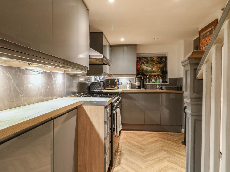 A kitchen with cabinets and stove at Jasmine Cottage in Matlock