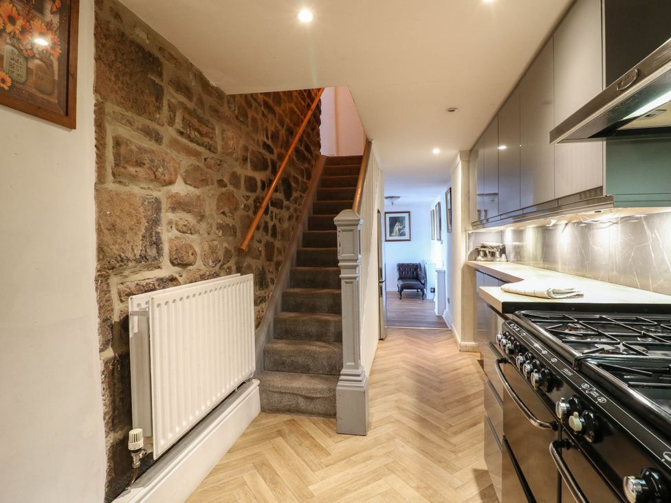 A kitchen with a stove and staircase at Jasmine Cottage in Matlock