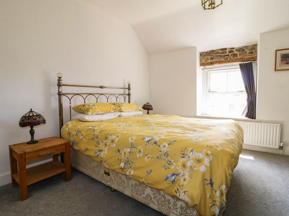 A bedroom with a bed and bedside table at Jasmine Cottage in Matlock