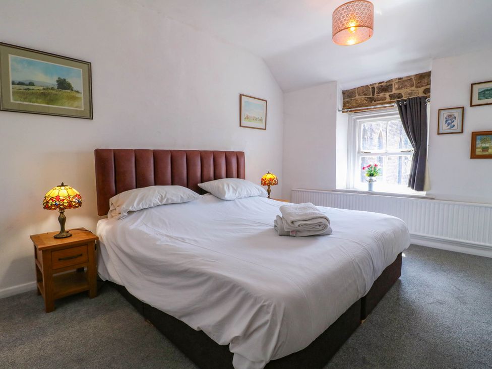A bedroom with a large bed and lamps at Jasmine Cottage in Matlock