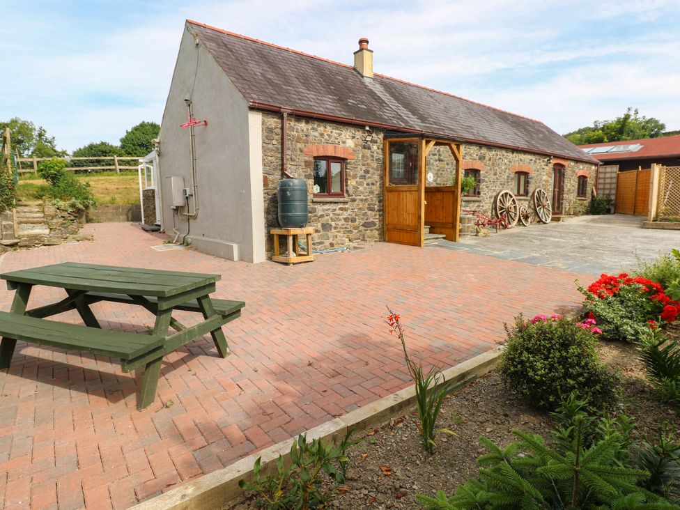 An outdoor area with a table and flowers at Coedllys Uchaf Cottage