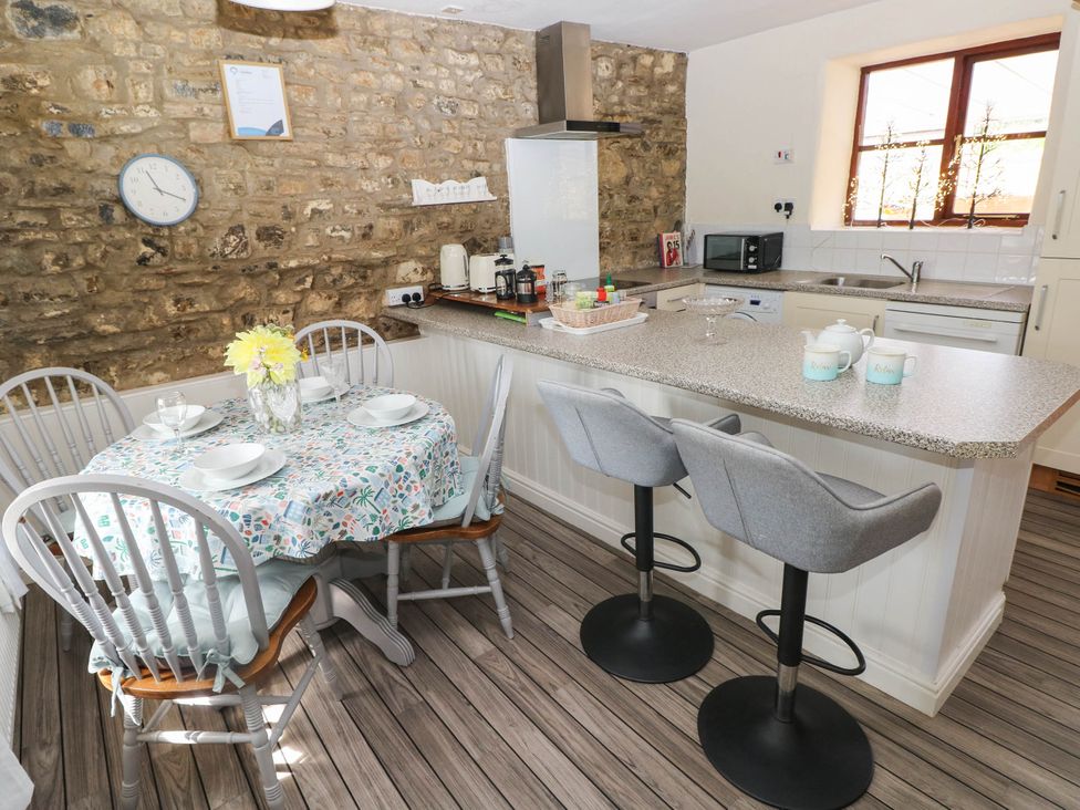 A kitchen with a dining table and bar stools at Coedllys Uchaf Cottage