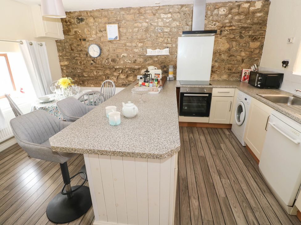 A kitchen with countertop, stove, stove hood and appliances at Coedllys Uchaf Cottage