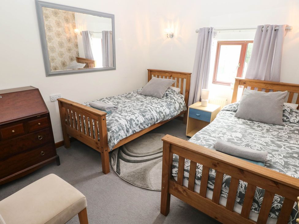 A bedroom with two wooden beds and a drawer at Coedllys Uchaf Cottage