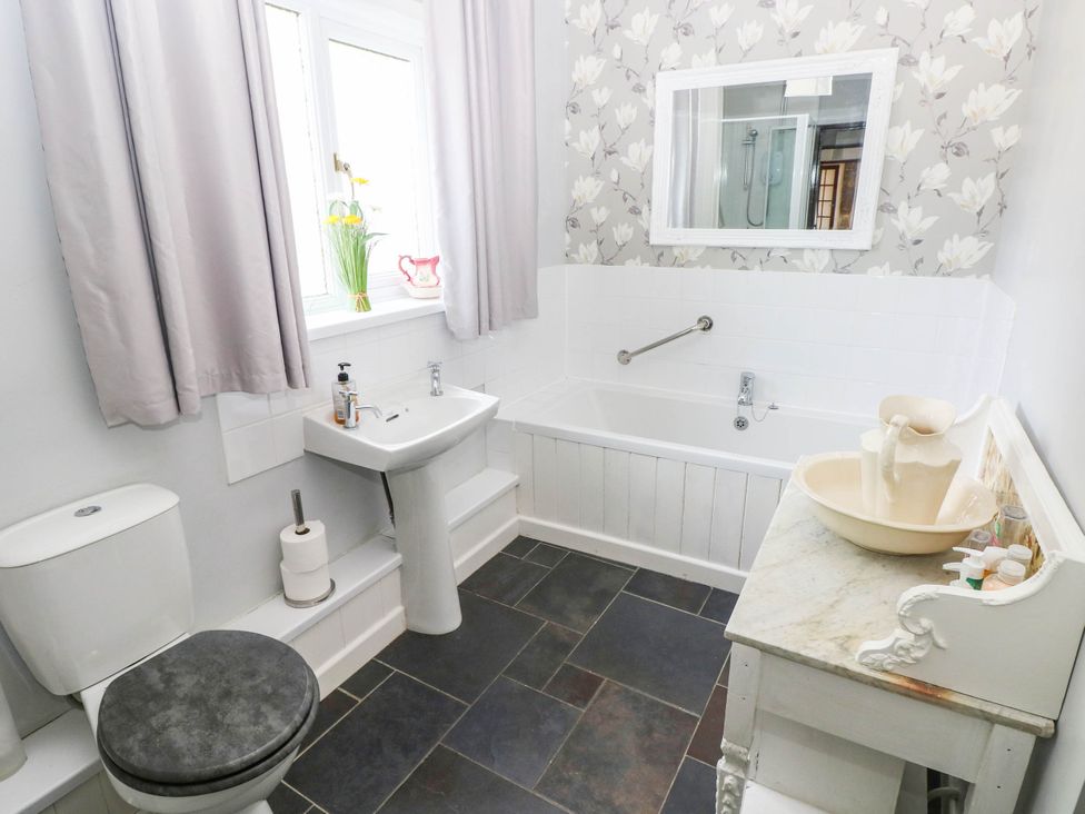 A bathroom with a bathtub, toilet, and sink at Coedllys Uchaf Cottage
