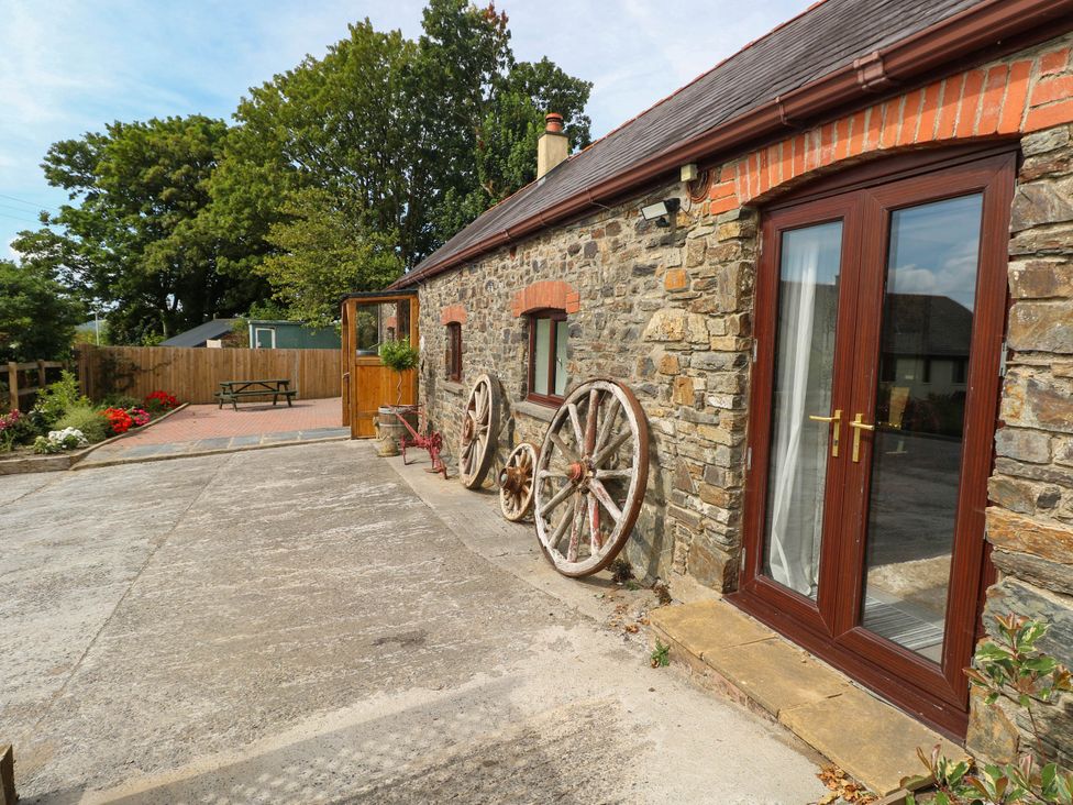 An outdoor area with a stone wall and wheels at Coedllys Uchaf Cottage