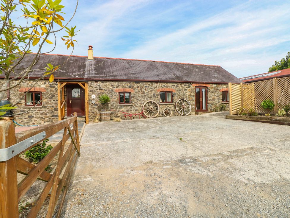 An outdoor area with a stone building and wooden wheels at Coedllys Uchaf Cottage