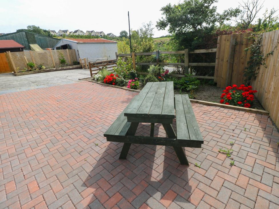 A table and bench in a garden area at Coedllys Uchaf Cottage