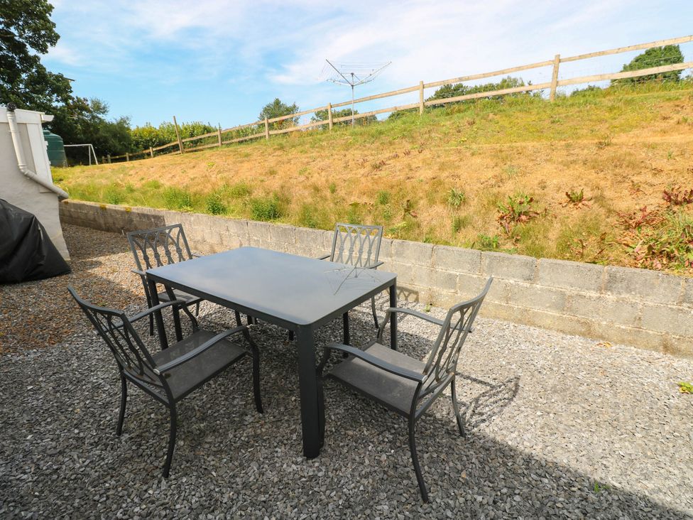 An outdoor seating area with a table and chairs at Coedllys Uchaf Cottage