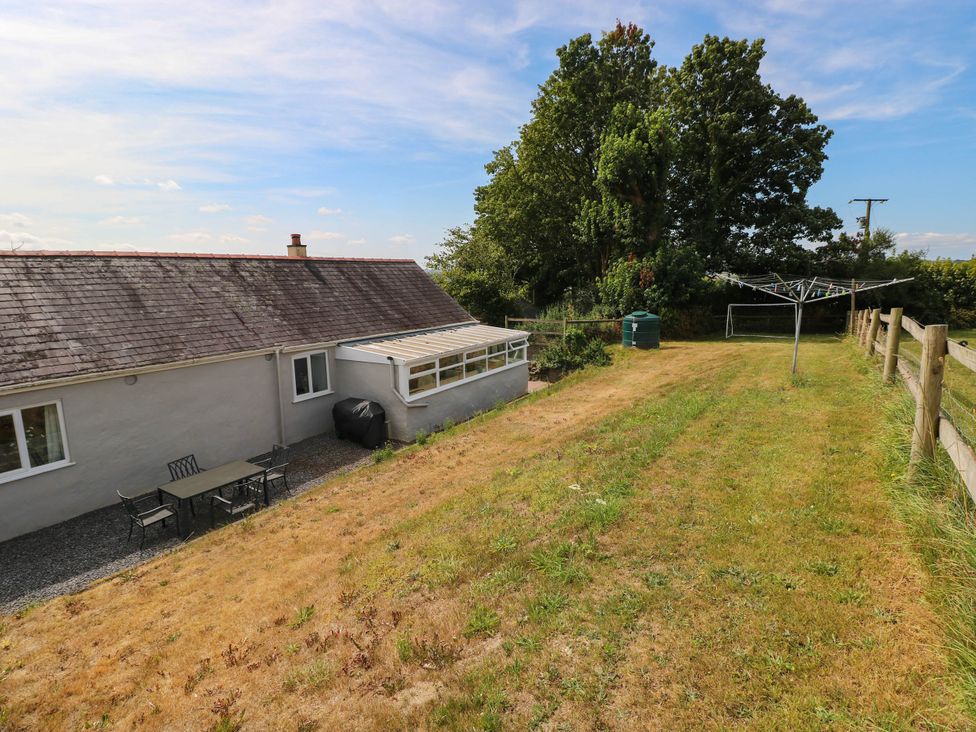A house with a table and chairs in the yard at Coedllys Uchaf Cottage