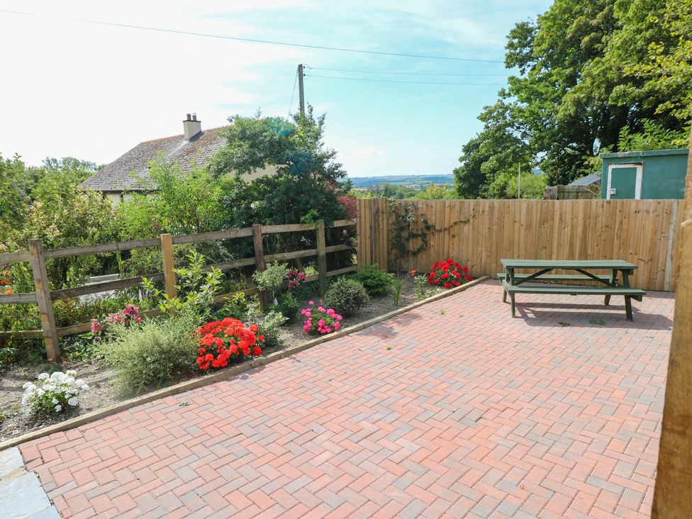 A garden with a table and flowers at Coedllys Uchaf Cottage