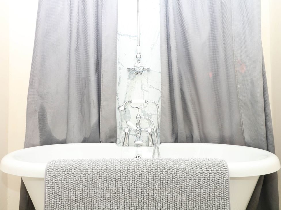 A bathtub with a faucet and gray towels at The Cheese House near Charmouth
