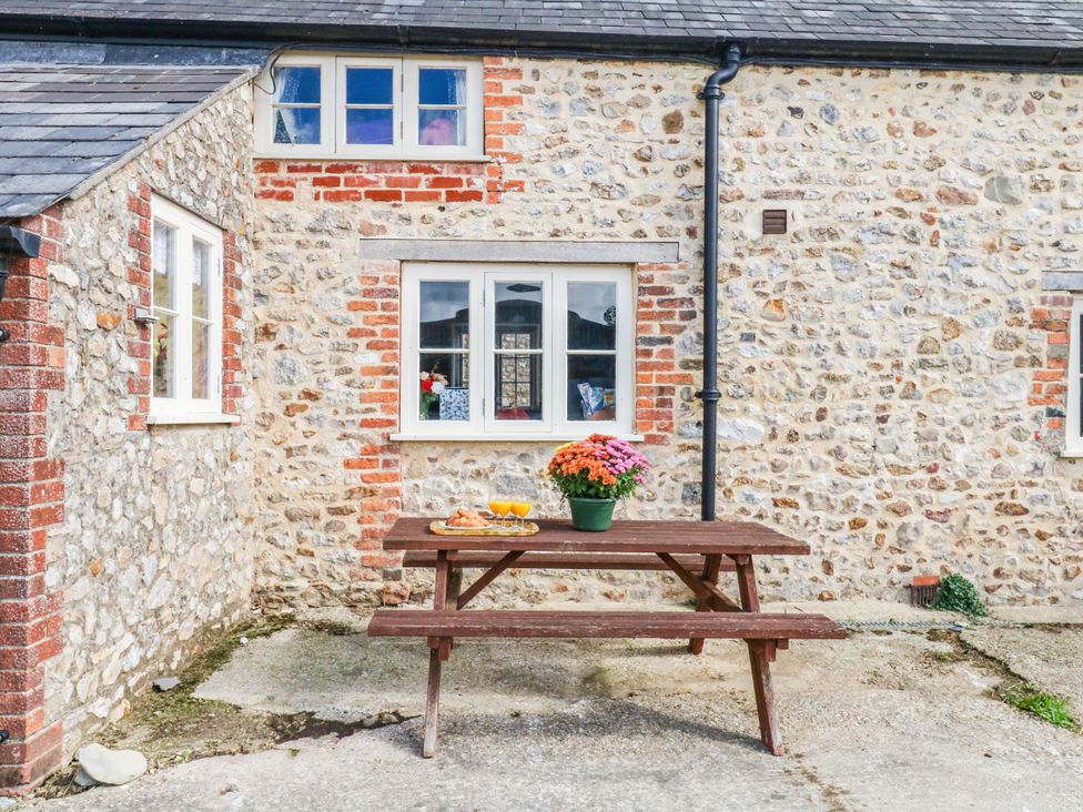 An outdoor area with a wooden table and flowers at The Cheese House near Charmouth