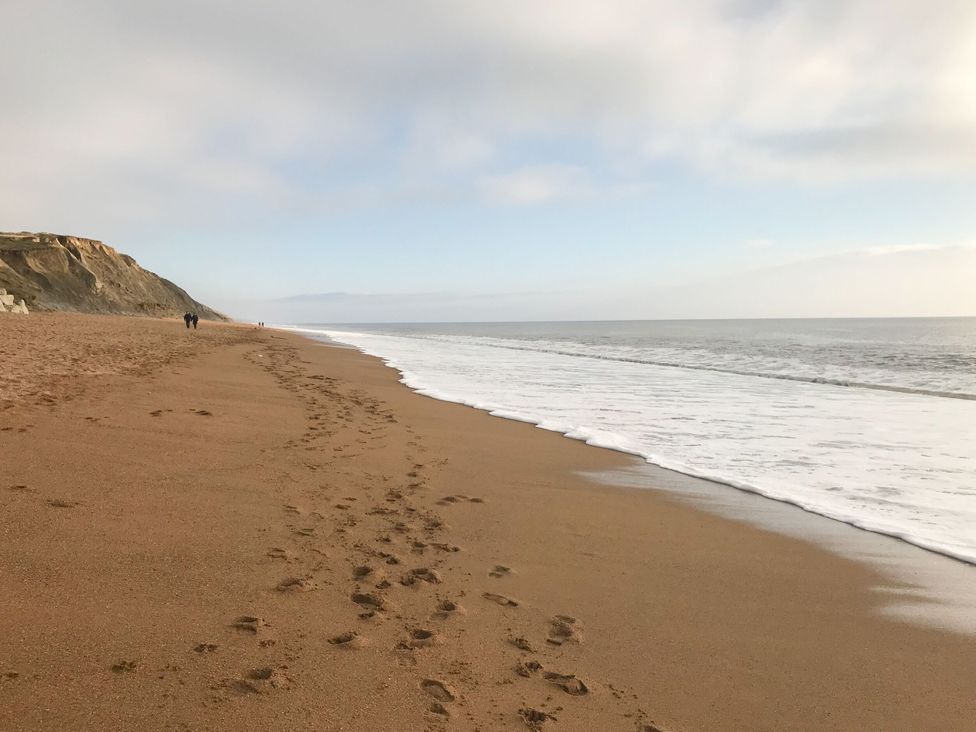 A beach with footprints and cliffs near the ocean at The Cheese House near Charmouth