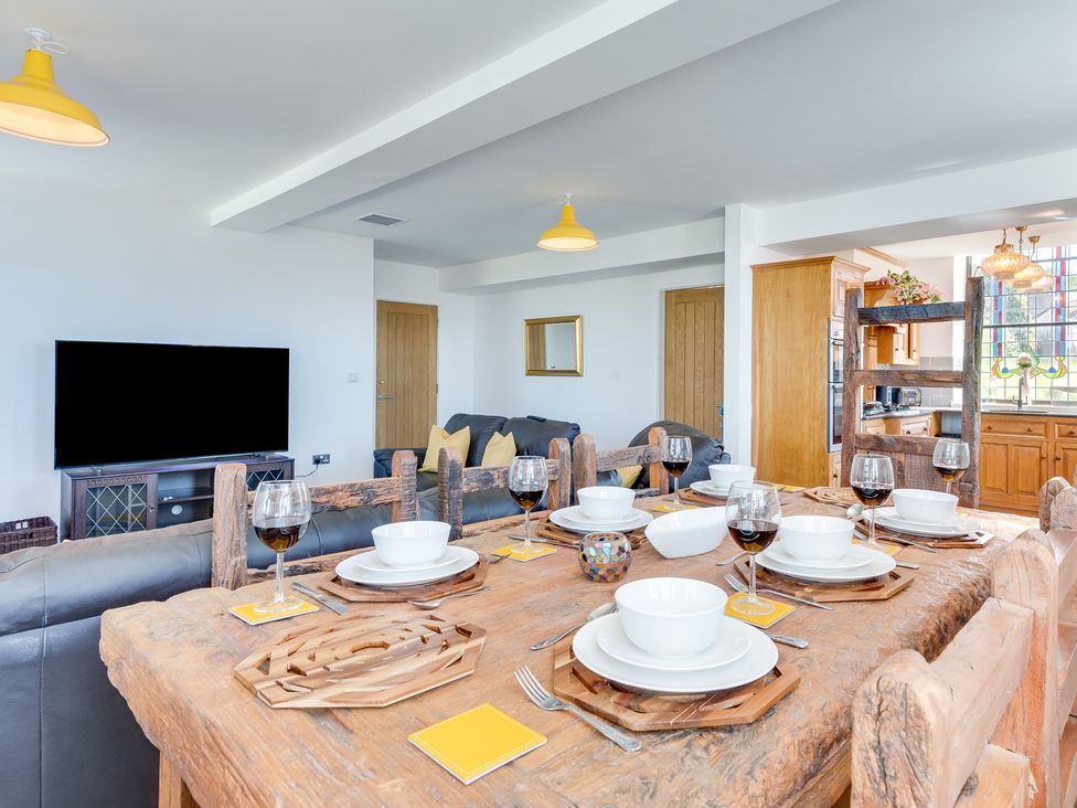 A dining room with a wooden table and TV at Birchover Chapel in Birchover
